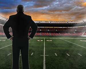 Hombre parado al lado de un campo de fútbol americano