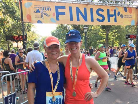 Dos corredoras de pie en la línea de meta en Women Run The Cities en Minneapolis