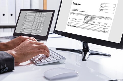 person using a computer with invoices on the screen