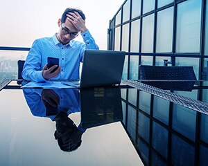 hombre estresado en la computadora con un teléfono
