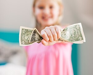 niña pequeña que sostiene billetes de dólar
