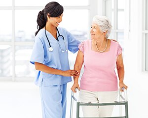 nurse assisting elderly woman with a walker
