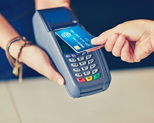 person holding their card and a small payment terminal