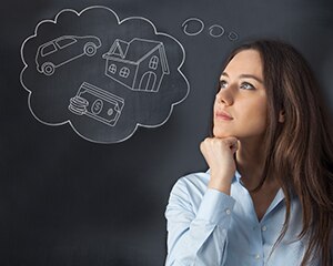 young woman with a thought bubble over head with a house, car and money in it