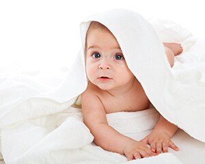bebé acostado sobre una manta blanca