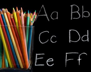 container of colored pencils with blackboard and letters