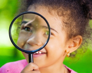 Young girl holds up magnifying glass