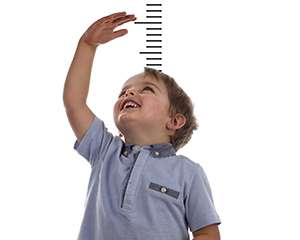 Photo of young boy reaching above his head to make himself look taller