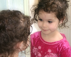 Young girl looks in the mirror