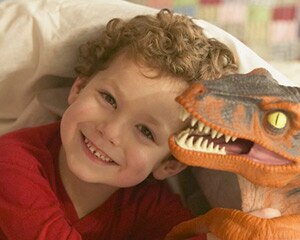 Foto de una niña pequeña jugando con un tiranosaurio rex de juguete