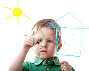 Young boy draws a house outline