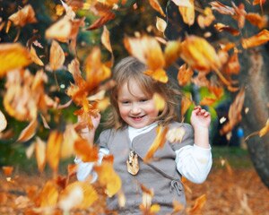 Foto de una niña lanzando hojas