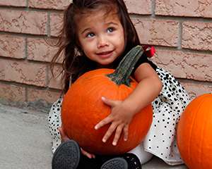 Photo of a little girl hugging a pumpkin