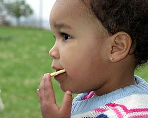 Photo of a young girl putting a cracker in her mouth