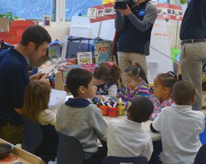 el maestro lee a los niños en un entorno de aula con cámaras de video presentes