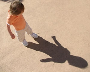 Little boy walking looking down at his shadow