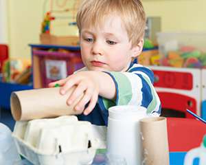 A boy using an old paper roll to build a structure