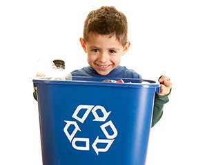 Niño sonriendo mientras carga una papelera de reciclaje llena
