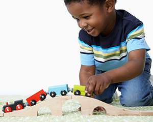 Niño joven jugando con un conjunto de trenes de madera