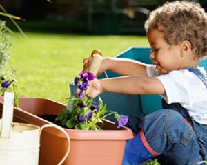 Niño joven colocando una planta en una maceta