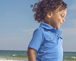 Little boy on beach with hair blowing in the wind