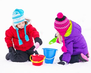 Niño y niña pequeña jugando con la nieve derritiéndose