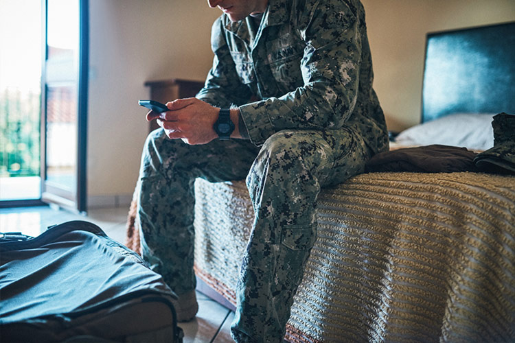 Miembro militar utilizando un teléfono inteligente en un hotel
