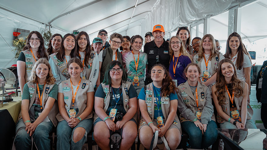 Scott Dixon posing with a group of Girl Scouts at a Girls at the Track Day