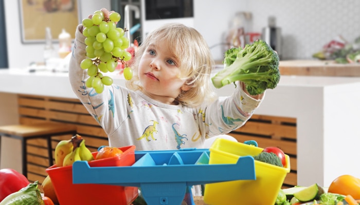 Child Comparing Bunch of Grapes to Broccoli