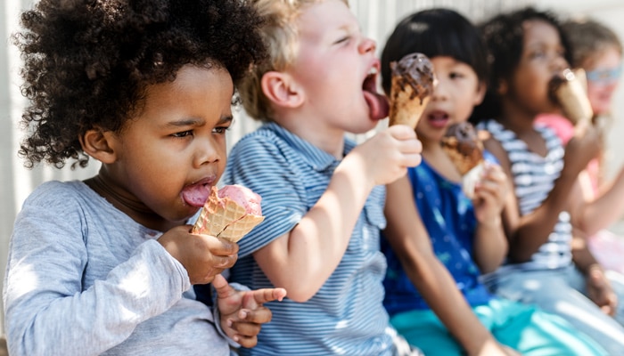 Group of toddlers sitting eating ice cream cones