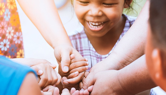 Small child holding hands with a group of children
