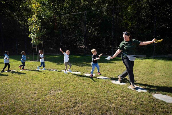 Nature based play and learning space in Pittsburgh where children are walking on stepping stones.