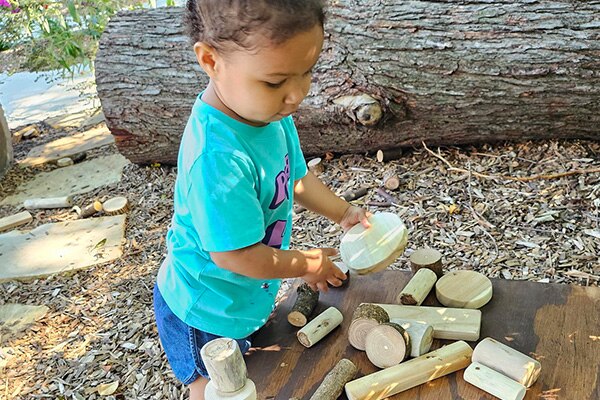 Nature based play and learning space in Kansas City with a child enjoying natural materials.
