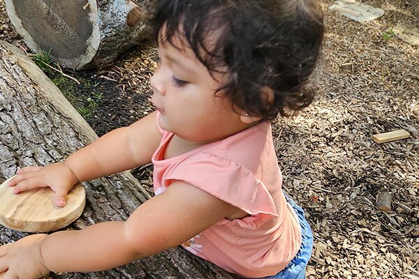 Nature based play and learning space in Kansas City with a child enjoying natural materials.