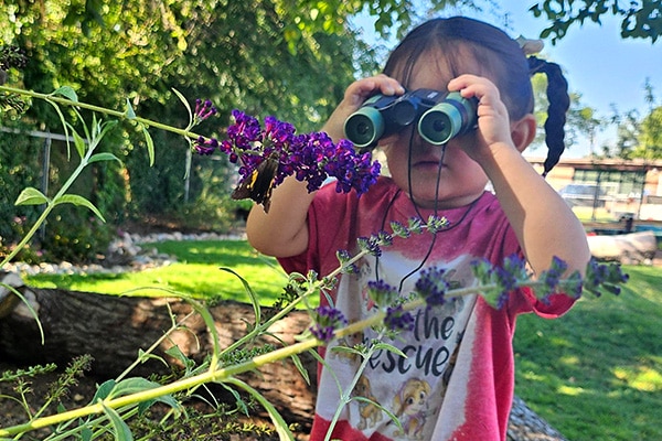 Nature based play and learning space in Kansas City with a child looking through binoculars.